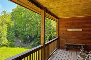 A wooden cabin with a balcony, a welcome sign, and a bench.