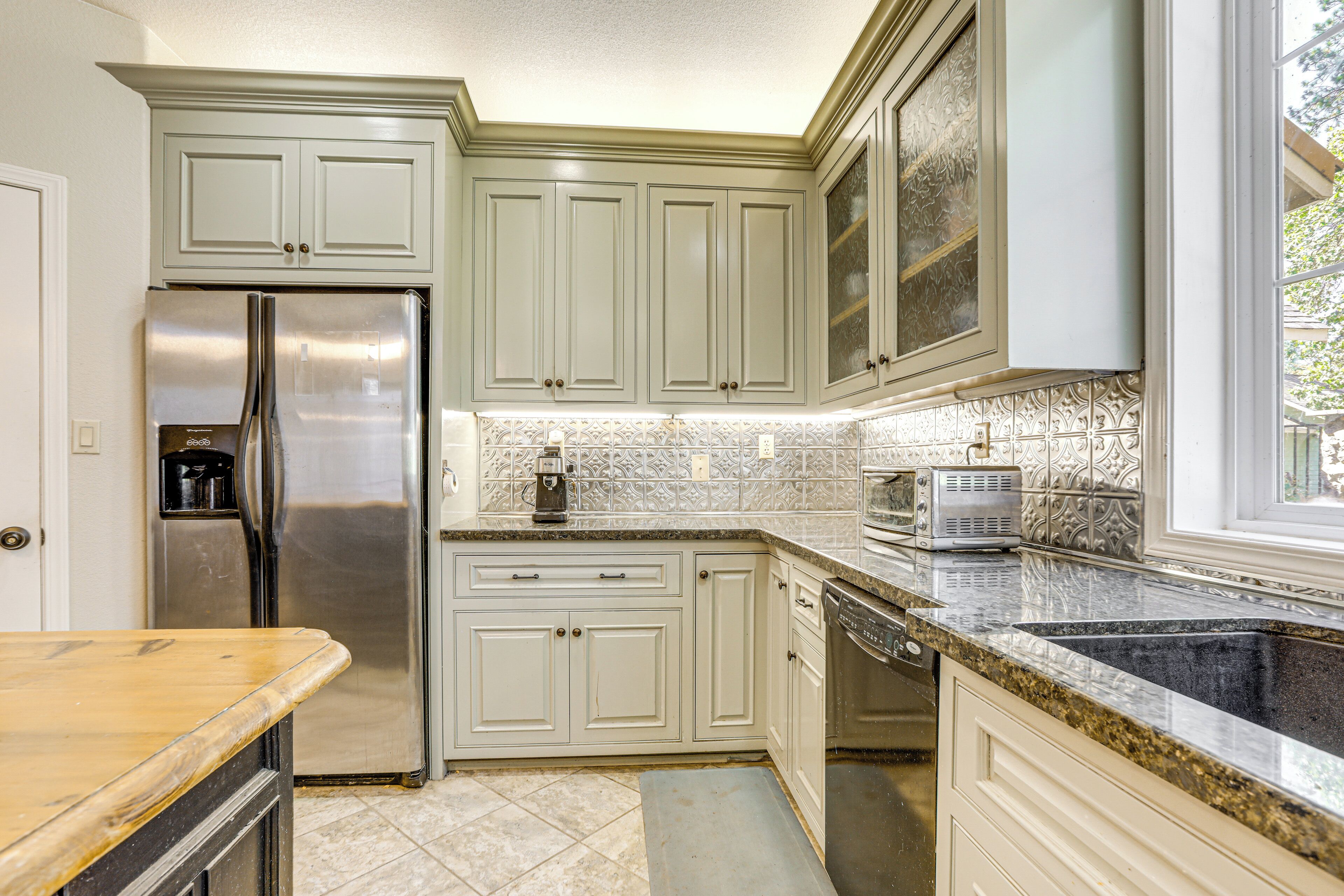A kitchen with white cabinets, stainless steel appliances, and a granite countertop.