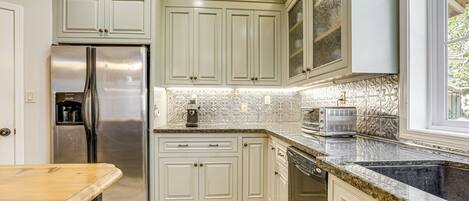A kitchen with white cabinets, stainless steel appliances, and a granite countertop.