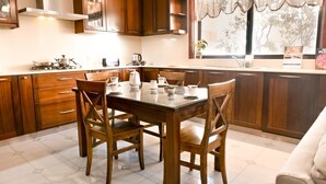A kitchen with wooden cabinets, a dining table with chairs, a gas stove, and a window with a view of trees.