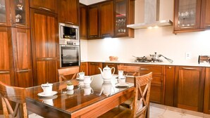A modern kitchen with wooden cabinets, a glass dining table, and white appliances.
