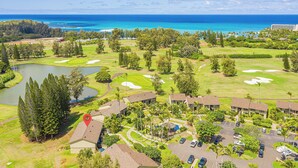 Un campo de golf con un lago, zona de estacionamiento y un hotel con varias edificaciones.