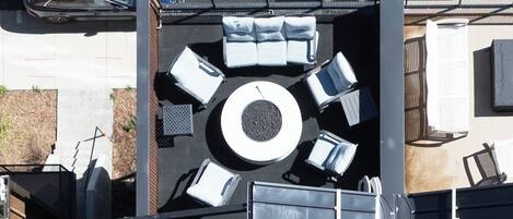 A rooftop terrace with a circular seating area, a small pool, and a view of parked cars.