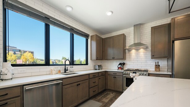 Una cocina moderna con azulejos blancos tipo metro, electrodomésticos de acero inoxidable y armarios de madera.