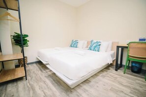 Hotelkamer met een bed, een tafeltje, een stoel, een plant en een plank.