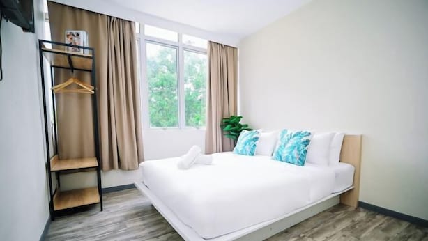 Ein modernes Schlafzimmer mit einem Bett, einer Holzregaleinheit, einem Fenster mit Vorhängen und einer Pflanze.