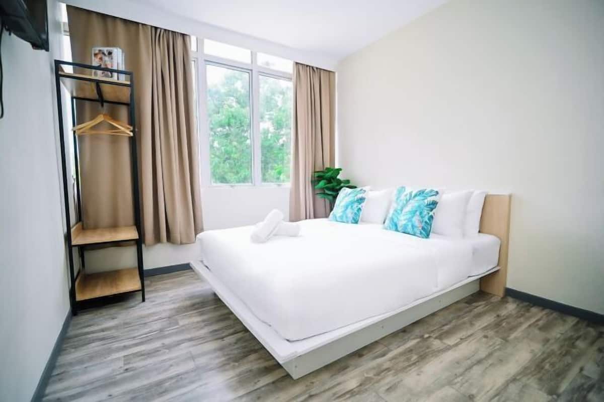 Een moderne slaapkamer met een bed, een houten plankunit, een raam met gordijnen en een plant.