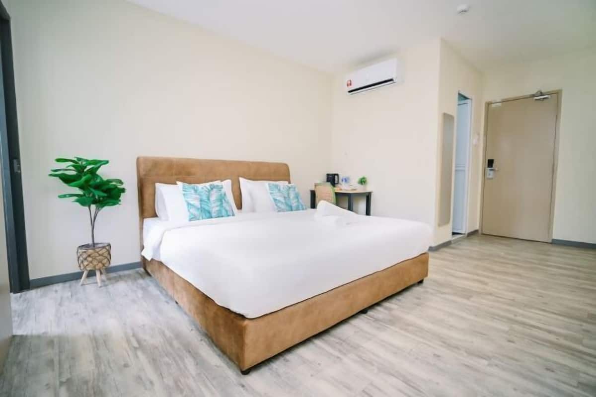 Een moderne hotelkamer met een groot bed, een klein bijzettafeltje, een potplant en een deur.