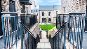 A staircase leading to a building with a brick facade and a small lawn area.