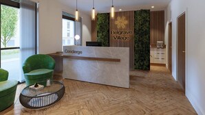A modern reception area with a marble counter labeled "Concierge," a green sofa, and a herringbone wooden floor.