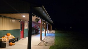 A rustic building with a covered porch, stone walls, and a red door. - Gather Here: 3,000 Sq Ft Lodge in Michigan's U.P. – Pond, Fire, Sleeps 14 (Wilson)