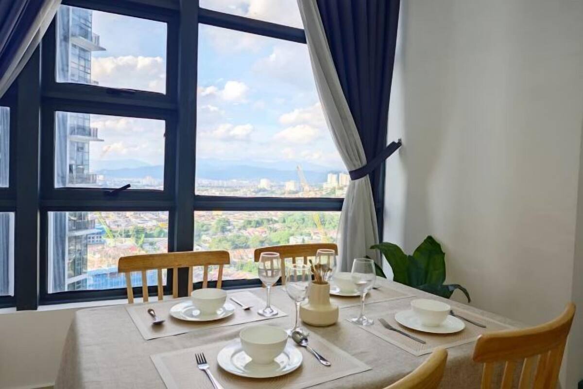 A dining table set for four with a view of a cityscape through large windows.