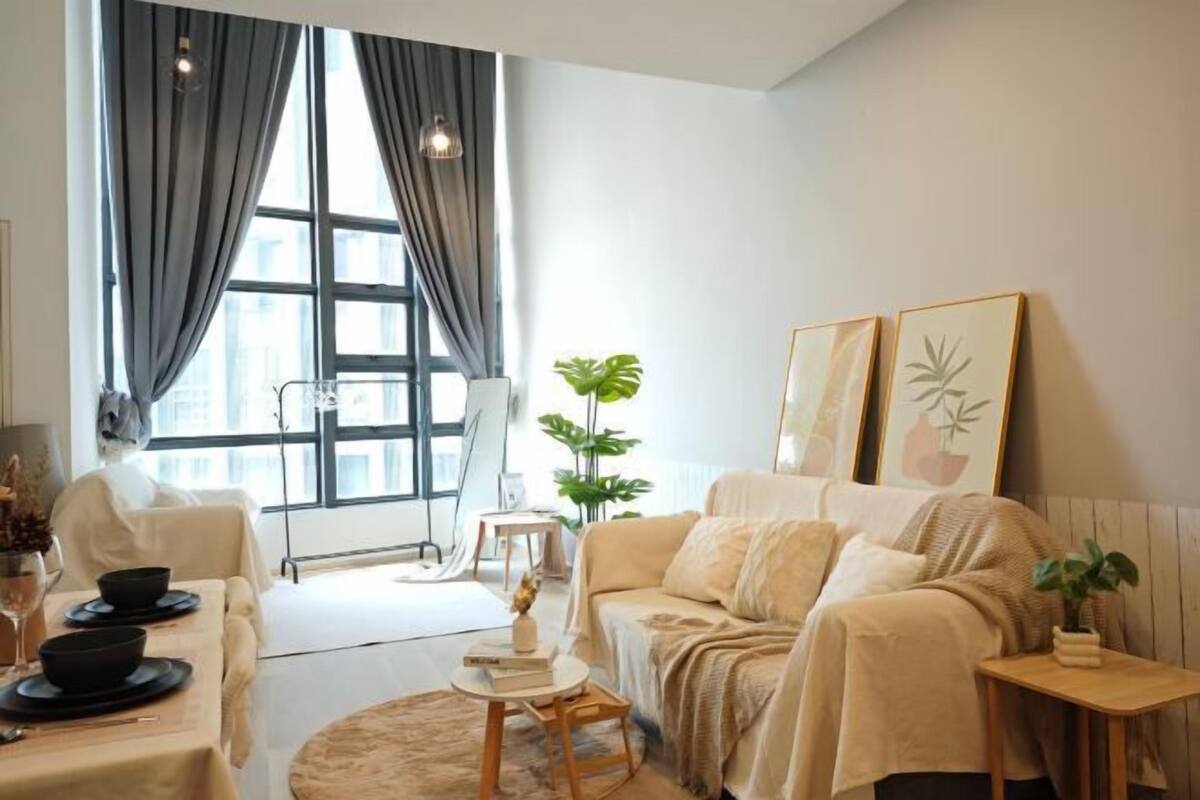 A modern living room with a sofa, a small round table, and a dining area with a table set for two.