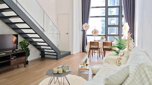 A modern living room with a staircase, a dining area, and a sofa with decorative pillows. - Urban Loft: MRT Convenience, KLCC Nearby @ Eko Cheras (Kuala Lumpur)