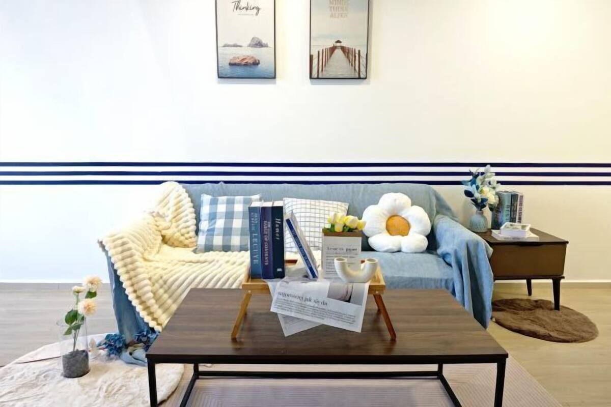 A cozy living room with a sofa, a coffee table, and a side table with books and a vase of flowers.