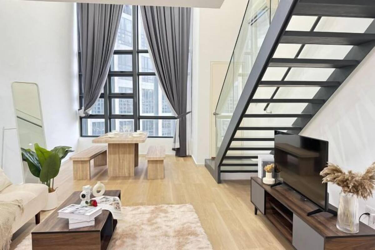 A modern living room with a sofa, coffee table, TV, and staircase.