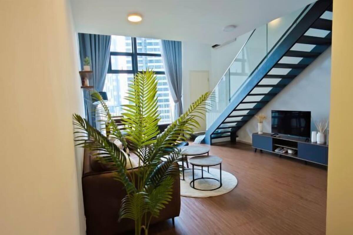 A modern living room with a staircase, a sofa, a coffee table, and a television.