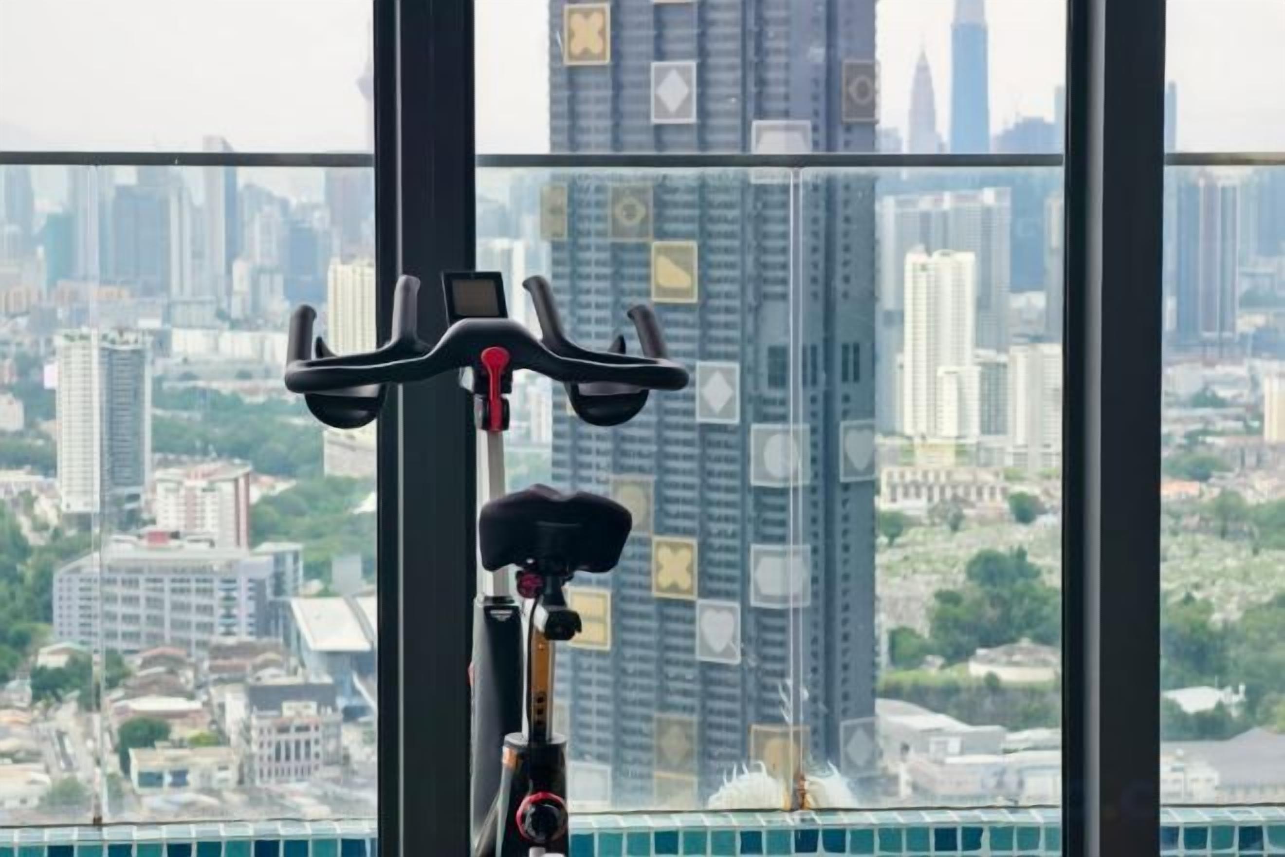 Una cyclette da allenamento con display digitale, posizionata davanti a una finestra con vista sulla città.