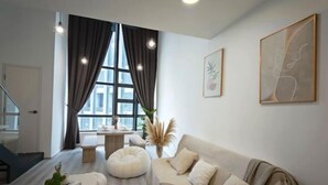 A modern living room with a sofa, a coffee table, and a large window with curtains. - Urban Loft: MRT Convenience, KLCC Nearby @ Eko Cheras (Kuala Lumpur)