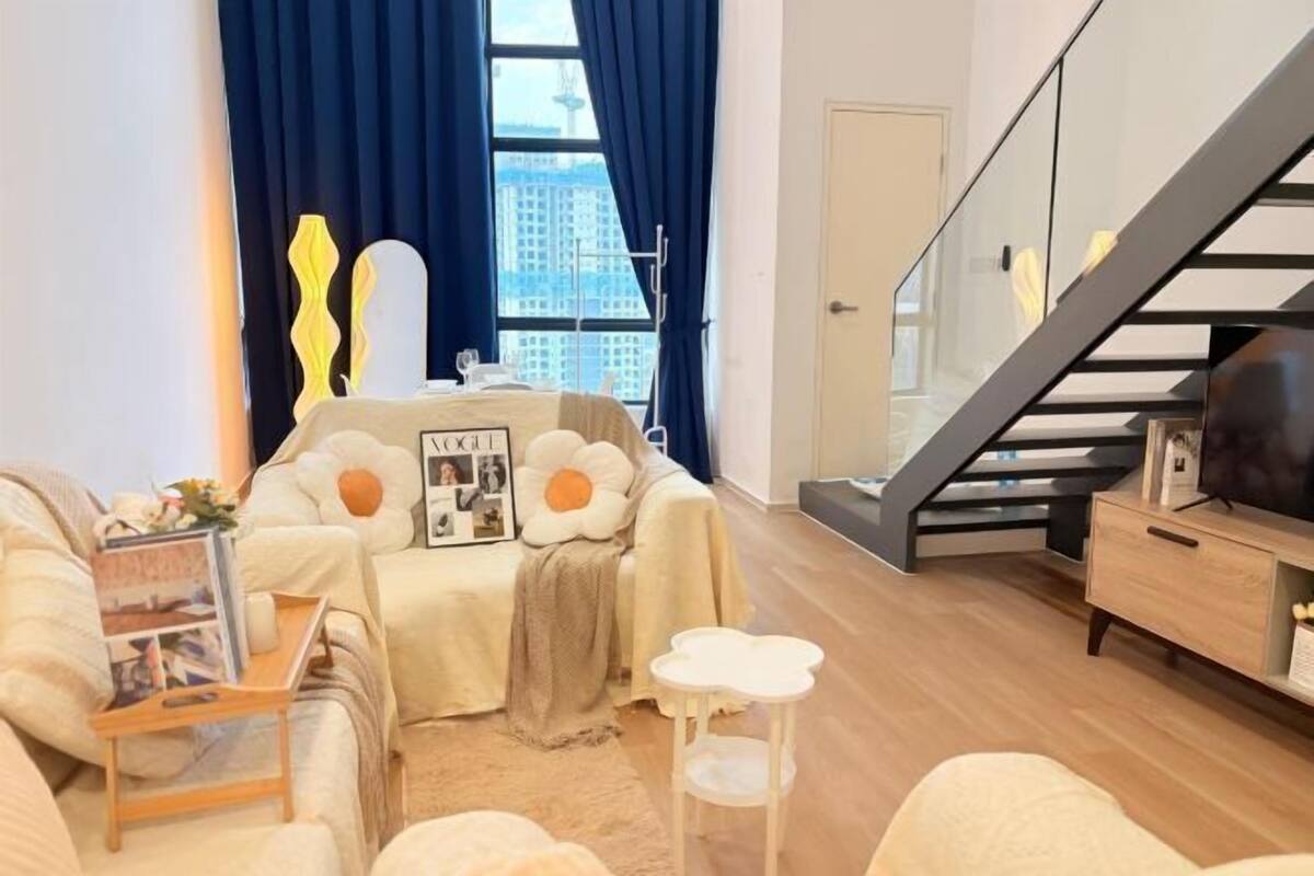 A modern living room with a sofa, a coffee table, a small side table, a TV, and a staircase.