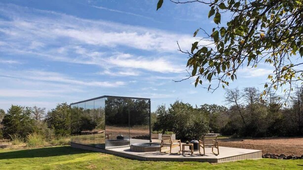 A modern outdoor patio with a glass enclosure, seating area, and fire pit. - RT Creekside Glass Retreat | Cowboy Pool/Hot Tub (Round Top)