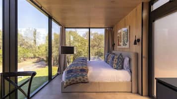 A modern bedroom with a large bed, a TV, and a view of the outdoors.