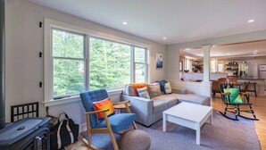A spacious living room with a large window, a sofa, a coffee table, and a rocking chair.