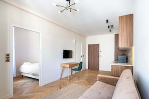 Ein modernes Wohnzimmer mit einer Couch, einem Schreibtisch, einem Fernseher und einer Küchenzeile.