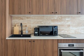 A modern kitchen with wooden cabinets, a microwave, a coffee maker, and a built-in oven.