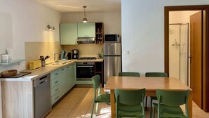 A compact kitchen with a dining area, featuring a microwave, stove, and cabinets. - Ground floor 2 (Propriano)