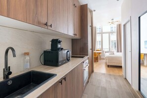 A modern kitchen with wooden cabinets, a black coffee machine, and a sink.