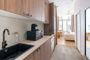Una cocina moderna con armarios de madera, una cafetera negra y un lavamanos.