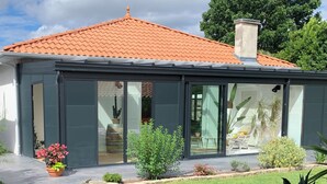 Een modern huis met pannendak, grote glazen deuren en een verzorgde tuin.
