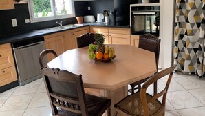 Een keuken met een eettafel voor twee personen, een vaatwasser en een koelkast.