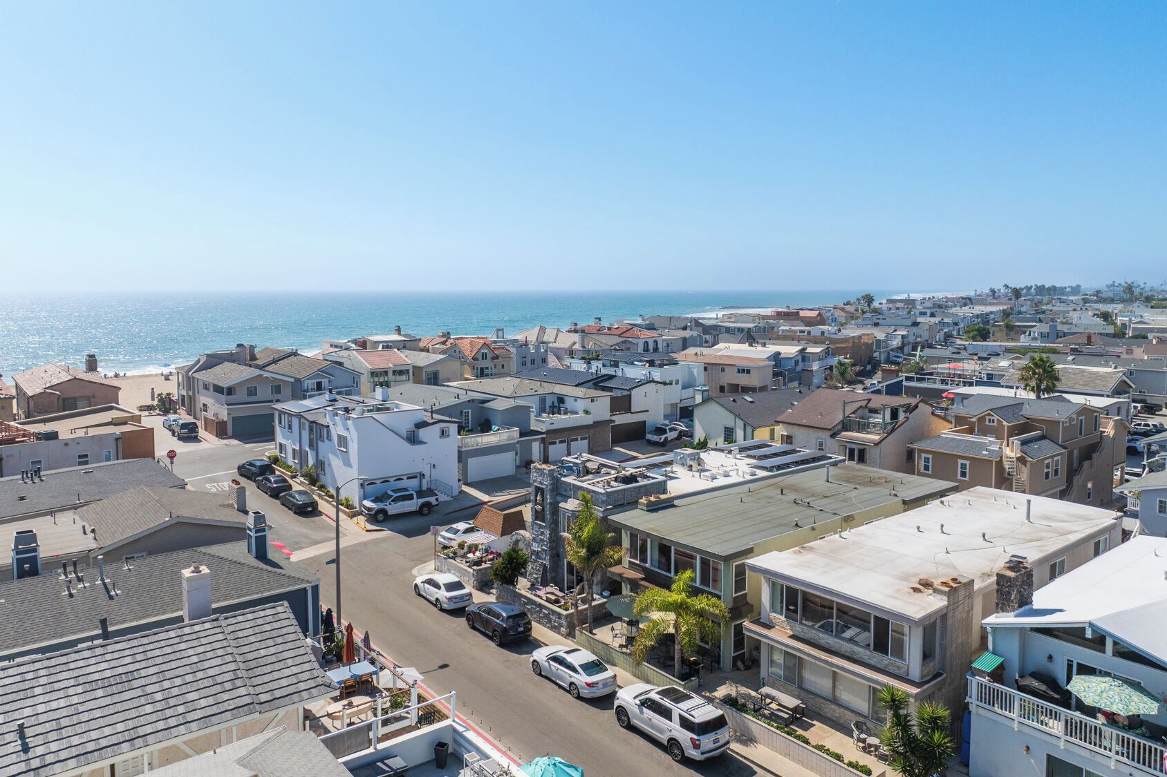 A coastal residential area with houses, a street, and a view of the ocean.