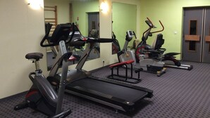 Ein Fitnessstudio mit Laufbändern, Crosstrainern und einem Spiegel.
