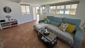 Uma sala de estar com um sofá, uma mesa de centro de vidro e um console branco com objetos decorativos.