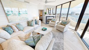 A spacious living room with a large window, a sofa set, a coffee table, and a fireplace. - East Pass Towers 602 3 Bedroom Condo (Destin)