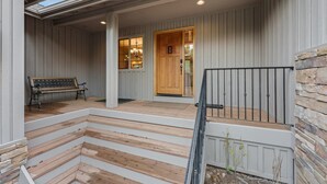 A wooden porch with a bench, a wooden door, and a stone wall. - 4 Tan Oak Lane 5 Bedroom Home (Bend)