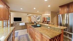 A spacious kitchen with wooden cabinets, a granite countertop, a stainless steel refrigerator, and a built-in stove. - 4 Tan Oak Lane 5 Bedroom Home (Bend)