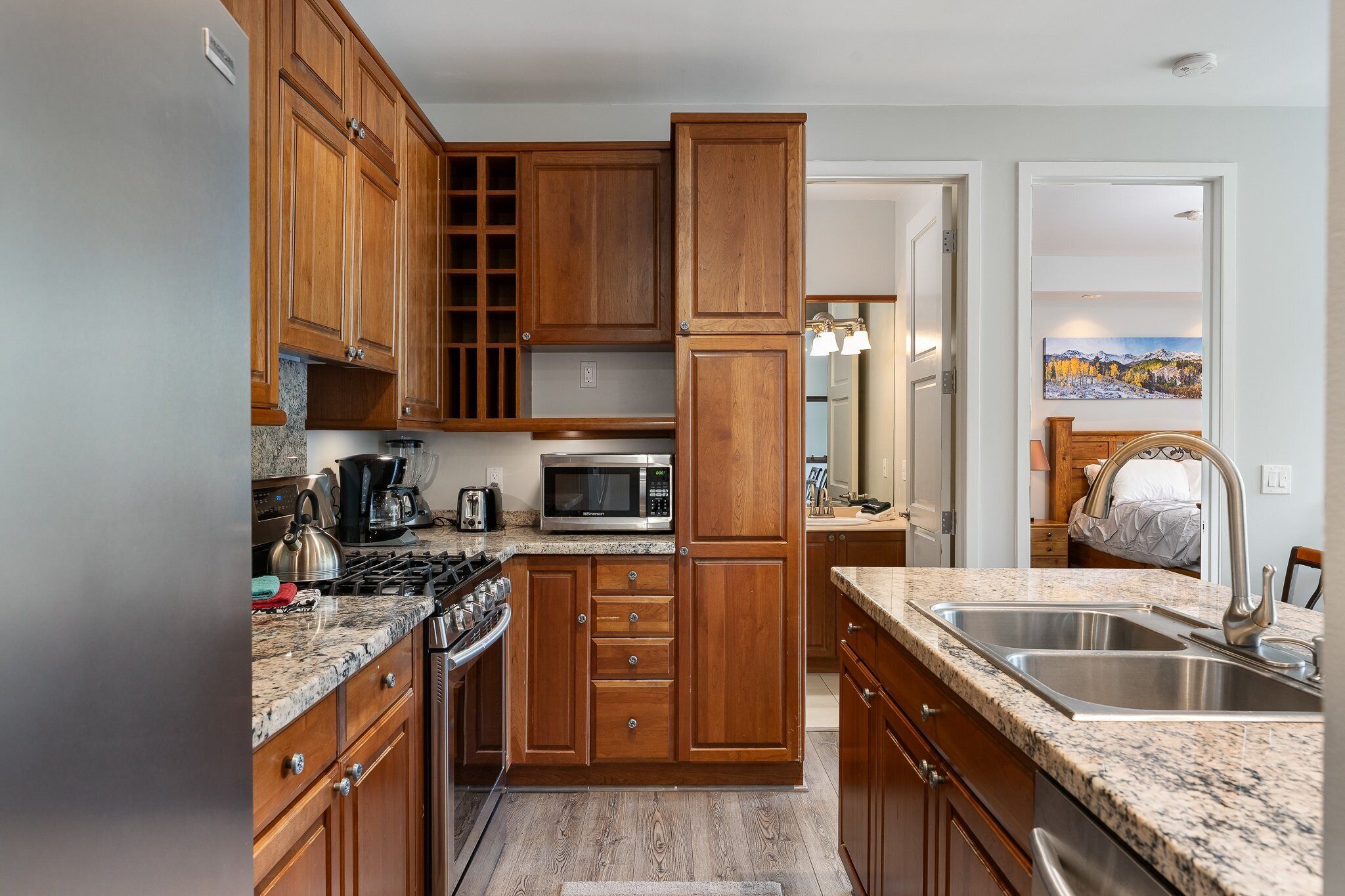 A kitchen with wooden cabinets, a granite countertop, stainless steel appliances, and a double sink.