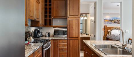 A kitchen with wooden cabinets, a granite countertop, stainless steel appliances, and a double sink.