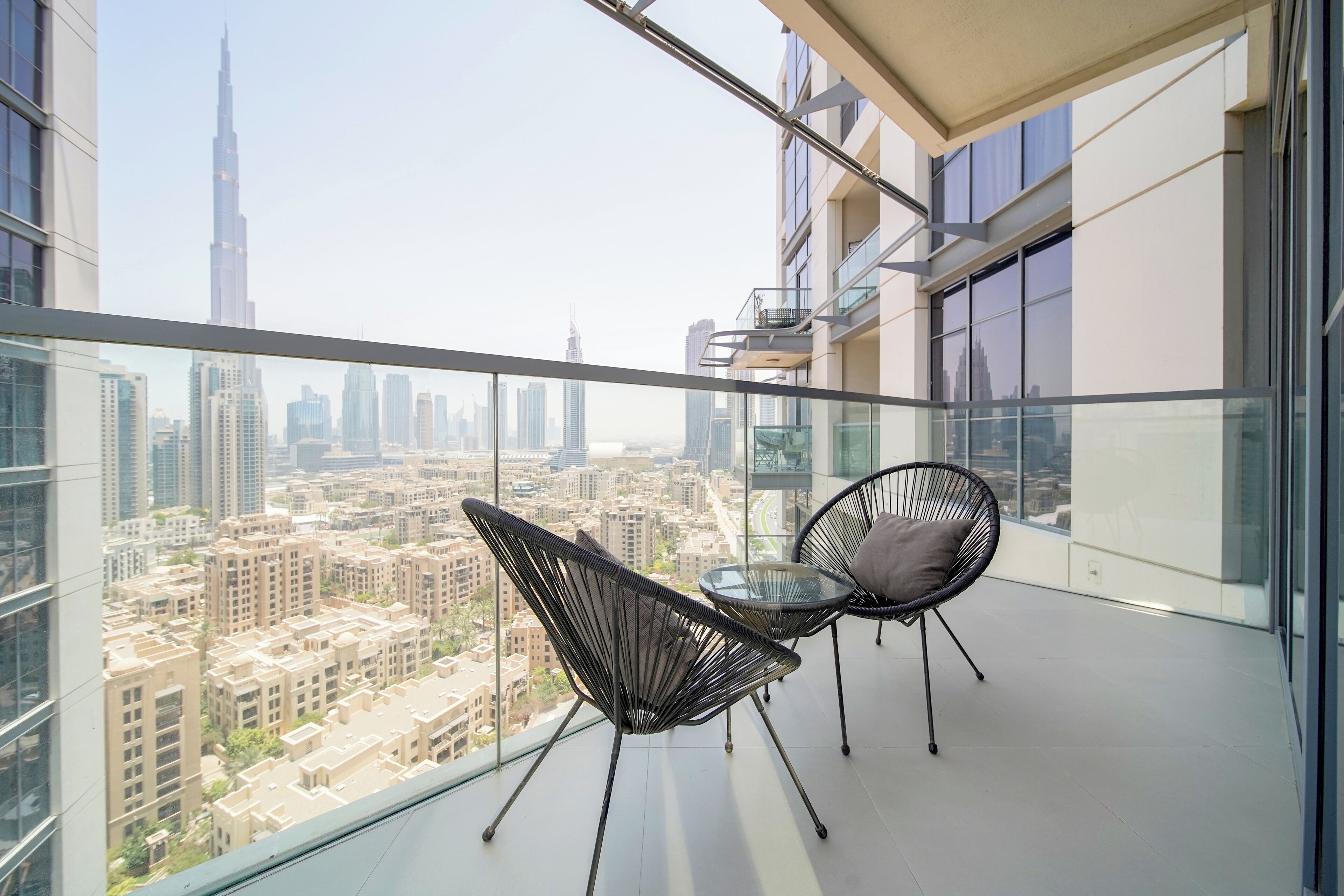 A balcony with two chairs and a table, offering a city view.