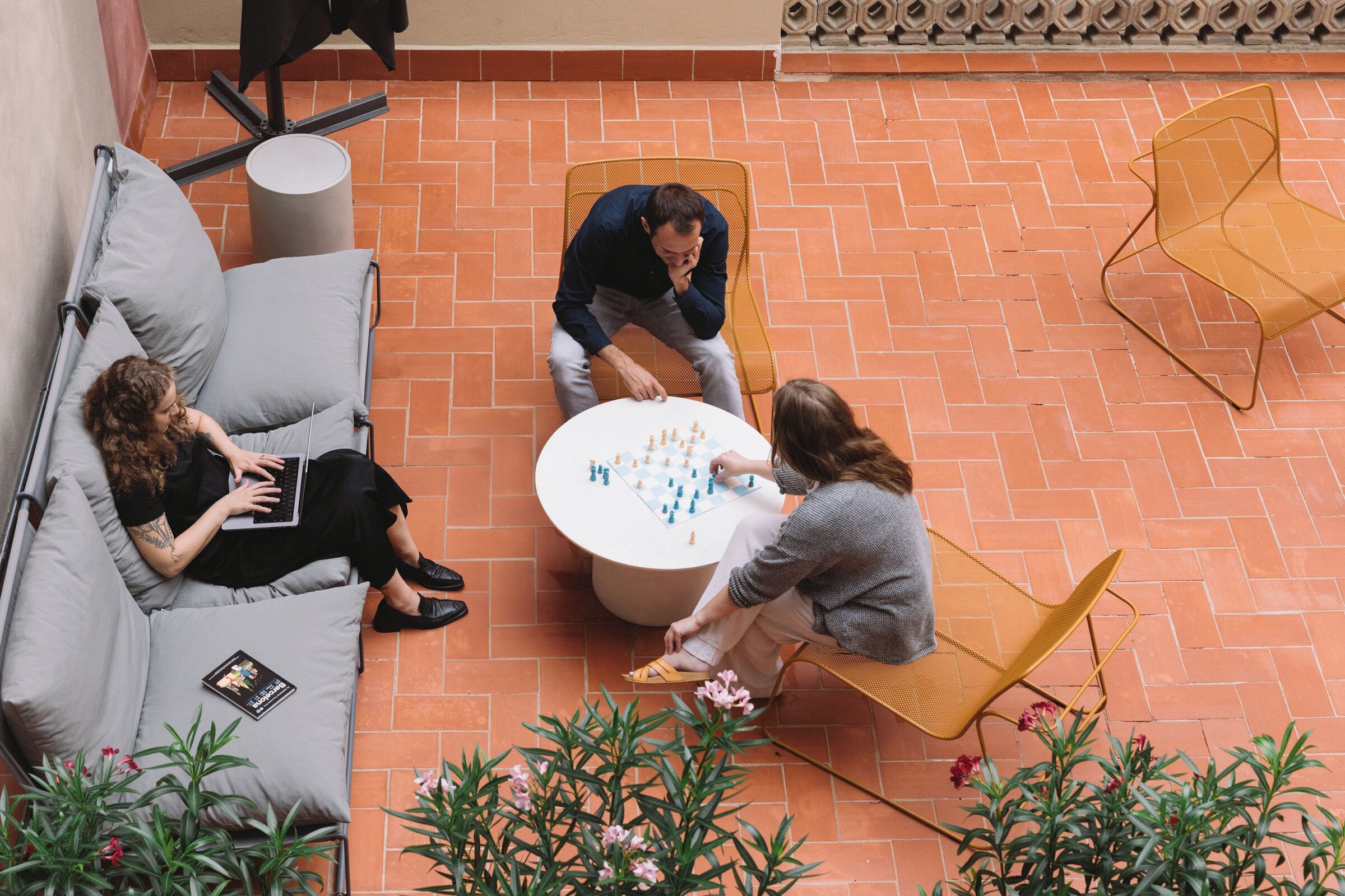 A patio area with a round table, two chairs, a sofa, and potted plants.