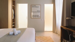 A hotel room with a bed, a desk, a chair, a TV, and a framed inspirational quote on the wall. - Outsite Barcelona - Work, Connect, Explore (Barcelona)