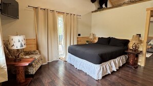 A bedroom with a bed, wooden ceiling, a mounted TV, and a bear decoration. - 5 Entire Cabins Retreat (Paris)