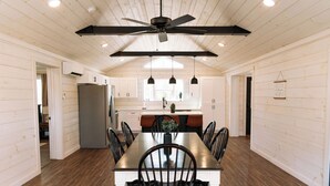Une cuisine spacieuse avec des meubles blancs, un îlot central et un ventilateur de plafond.