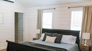Une chambre à coucher comprenant un lit, un banc, un ventilateur de plafond, une table de chevet et une fenêtre.