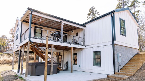 Une maison moderne à deux étages, dotée d’un porche couvert, d’un jacuzzi et d’un escalier menant à l’étage supérieur.