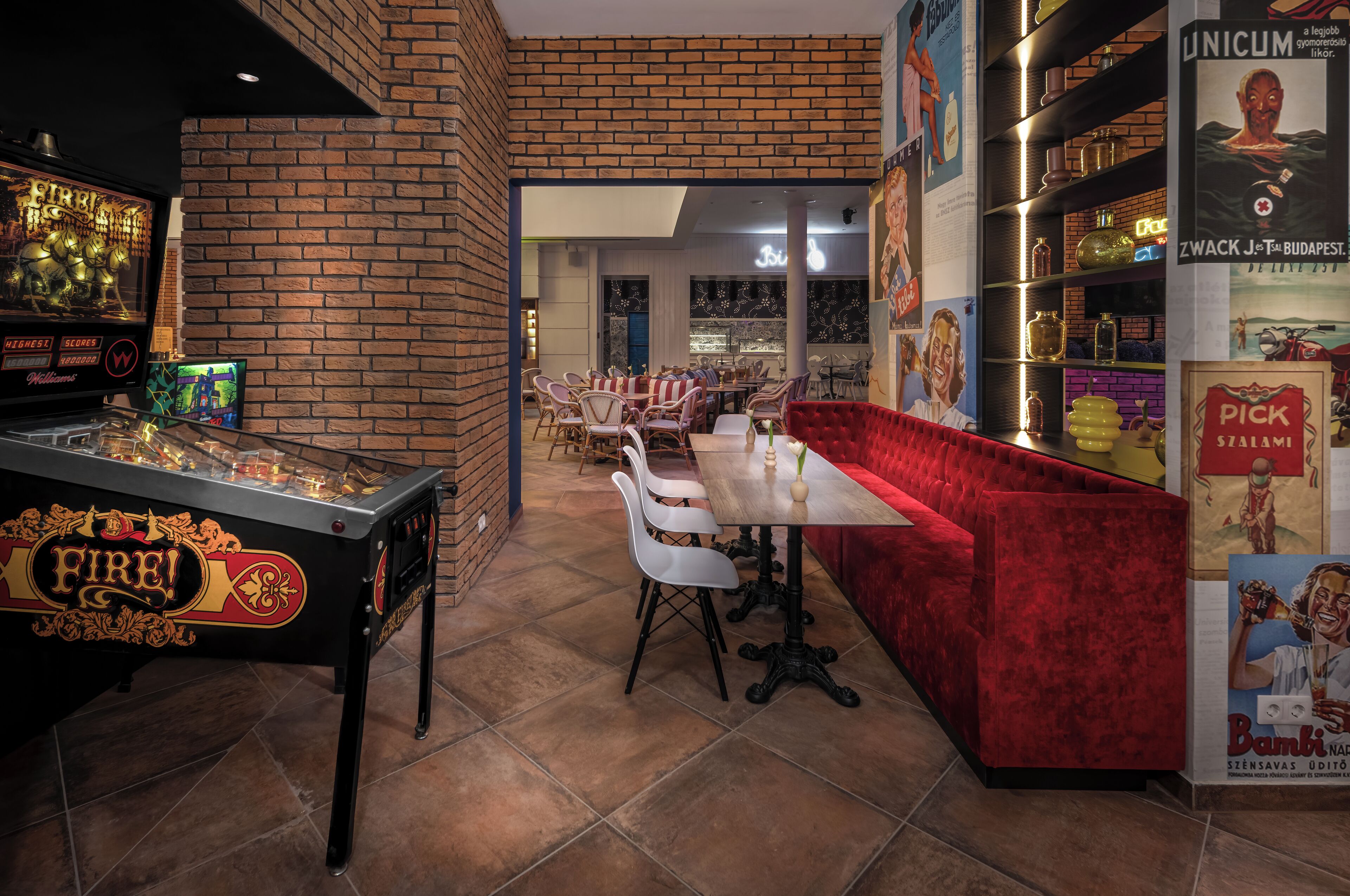 Una mesa de billar con temática 'Fire!', un sofá de terciopelo rojo y una zona de bar con estanterías y botellas.